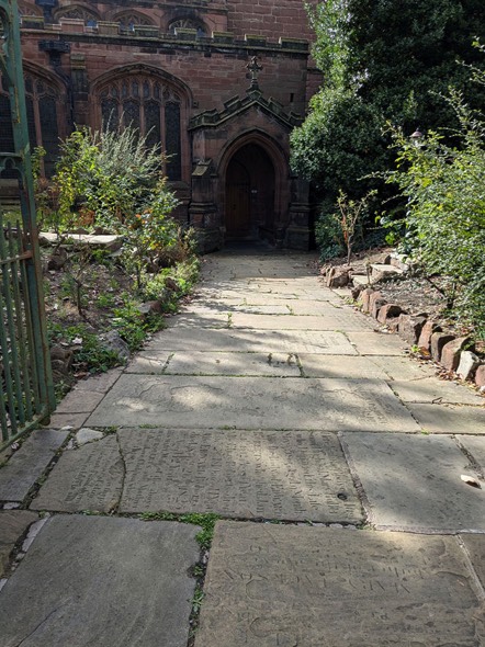 A photograph taken from the entrance gate showing the paved slope towards the door of St Mary’s